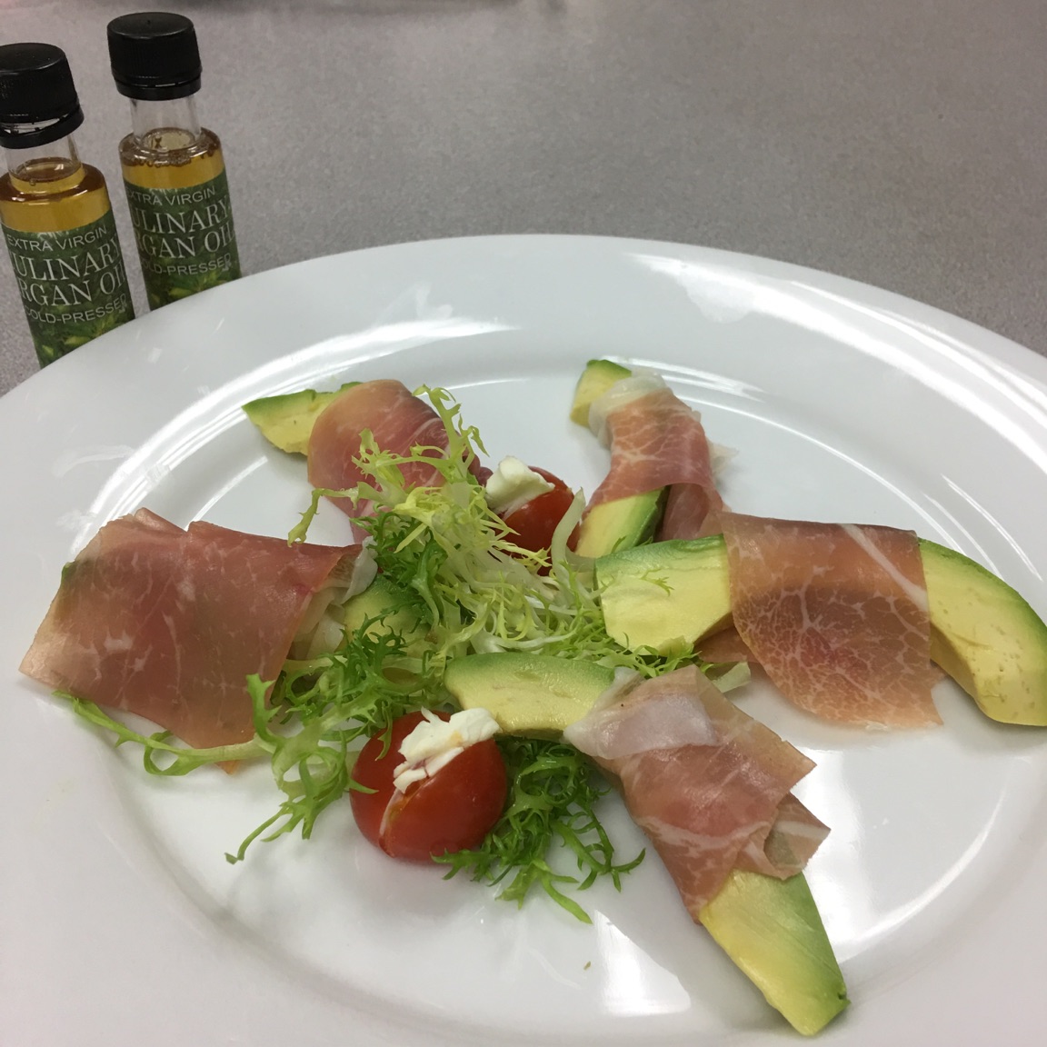 AVOCADO WRAPPED IN PROSCIUTTO HAM WITH A SIDE OF FRISEE SALAD FEATURING ARGAN OIL